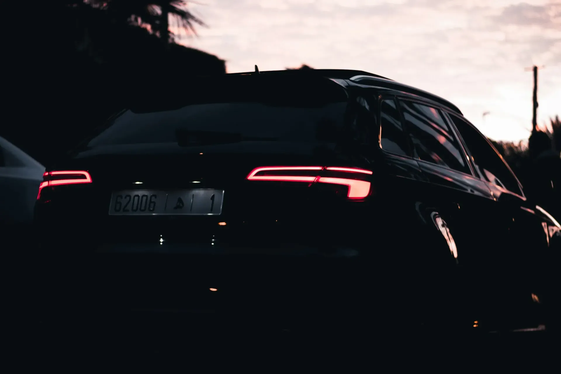 Dunkler Audi in der Abenddämmerung, Rückleuchten leuchten